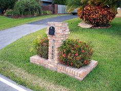 a brick mailbox in the middle of some grass