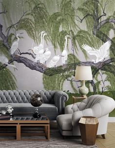 a living room filled with furniture and wallpaper covered in white cranes on trees