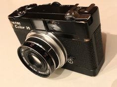 an old camera sitting on top of a white table next to a black object with the words fujita color 35