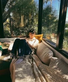 a woman sitting on top of a couch next to a window filled with lots of windows