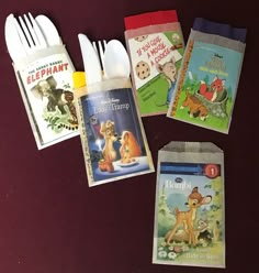 five children's books and plastic utensils laid out on a purple surface