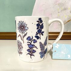 a blue and white coffee cup sitting on top of a table next to a tag