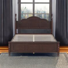 a bed sitting in front of a window next to a wooden frame and headboard