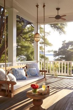 a porch swing with pillows and flowers on it