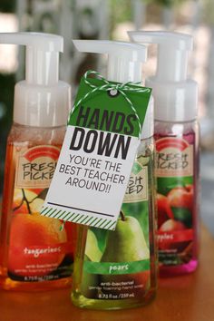 three bottles of hand sanitizers sitting on top of a wooden table next to each other