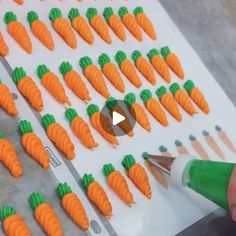 someone is drawing carrots on a sheet of paper with green and orange colored markers