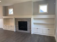 empty living room with fireplace and built - in shelving