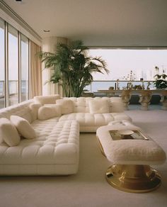 a living room filled with white furniture and large windows