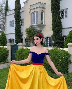 a woman in a yellow and blue dress is posing for the camera with her hands on her hips