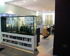 an aquarium in the middle of a room with bookshelves and pictures on the wall