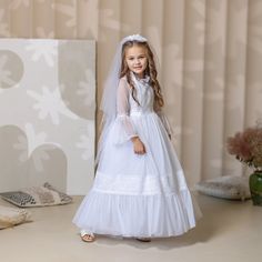 When it comes to a special occasion like a First Communion, finding the perfect dress and veil for your little girl is essential. A white First Communion dress and veil are traditional choices that symbolize purity and grace. For a classic and elegant look, consider opting for a tulle flower girl dress. The delicate fabric adds a touch of whimsy and creates a dreamy silhouette as your daughter walks down the aisle. The soft layers of tulle give the dress an ethereal feel, making it perfect for t Veiled Girl, Lace Flower Girl Dress, Holy Communion Dresses, Baptism Outfit, First Communion Dress, Tulle Flower Girl, Tulle Flowers, Soft Layers, Flower Girl Dress Lace