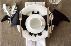 a white plate topped with a bat cut out next to a cup and saucer