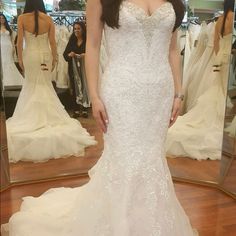 a woman standing in front of a mirror wearing a wedding dress