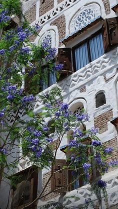 an ornate building with blue flowers in the foreground