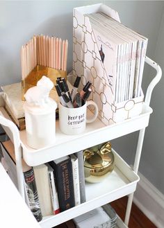 a white shelf with books, cups and other items on it