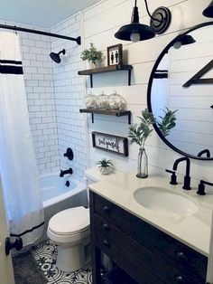 a bathroom with black and white tile flooring, a round mirror over the toilet