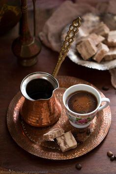 two cups of coffee on a plate next to some sugar cubes and cinnamon sticks