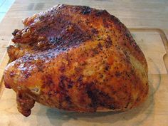 a cooked chicken sitting on top of a wooden cutting board