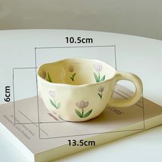 a coffee cup sitting on top of a book with measurements for the size and shape