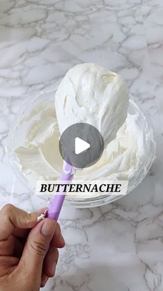 a person is holding a spoon in front of a bowl with whipped cream on it