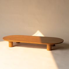 a wooden surfboard sitting on top of a white floor next to a light colored wall