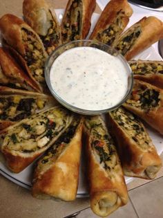 a white plate topped with pastries covered in toppings next to a bowl of ranch dressing