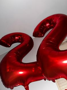 the number twenty two is made out of shiny red foil balloons and sits on a white surface