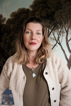 a woman standing in front of a painting with trees on the wall and her eyes closed