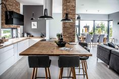 an open kitchen and living room with wood flooring, white walls and gray chairs