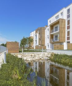 an apartment complex with water and grass in the foreground