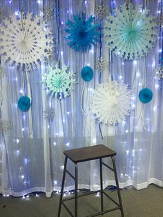 some snowflakes are hanging on the wall behind a chair in front of a curtain