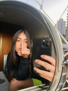 a woman taking a selfie in front of a mirror with her cell phone up to her face