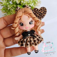 a hand holding a small doll with leopard print on it's head and hair