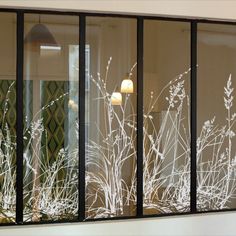 frosted window panes with white flowers and grass behind them in an office building