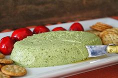 a plate with crackers and dip on it next to cherry tomatoes, crackers and strawberries