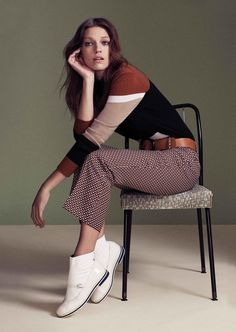 a woman is sitting on a chair with her legs crossed and looking at the camera