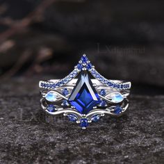 a blue and white diamond ring sitting on top of a black stone surface with diamonds around it