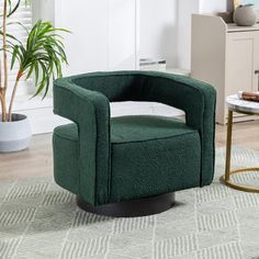 a green chair sitting on top of a rug next to a table and potted plant