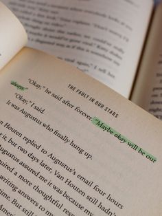 an open book with green writing on the page and two other books next to it