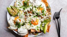 a white plate topped with nachos and eggs