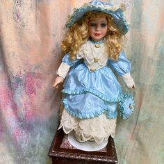 a doll sitting on top of a wooden table next to a wall covered in pink and blue paint