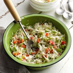 a green bowl filled with coleslaw and carrots