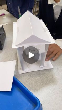 a person cutting out a paper house with scissors