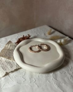 two wedding rings sitting on top of a white plate next to an open book and paper