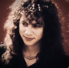 a woman with long curly hair posing for the camera