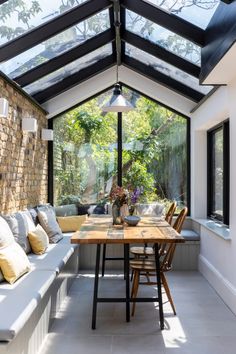 a room with a table, couches and windows on the outside wall is lit by a large skylight