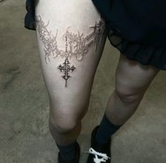 a woman's thigh with a cross tattoo on it