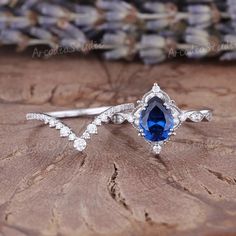 a blue and white ring sitting on top of a piece of wood next to flowers