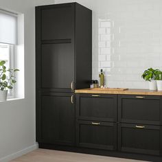 a kitchen with black cabinets and wooden counter tops