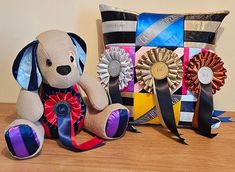 a stuffed dog sitting next to a pillow with ribbons on it's sides and a prize ribbon in front of it